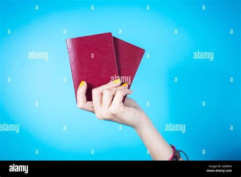 Womans Hand Holding A Two Red Passports Against Blue Background Stock