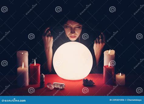 Soothsayer Using Glowing Crystal Ball To Predict Future At Table In