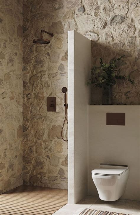 A White Toilet Sitting Next To A Stone Wall In A Bathroom Under A