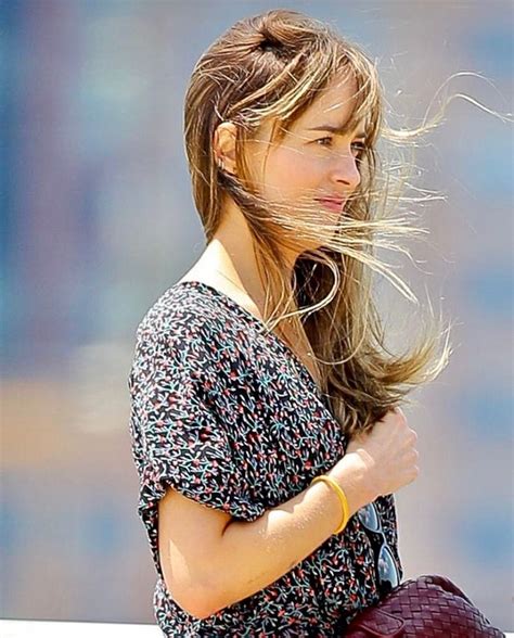 A Woman With Her Hair Blowing In The Wind While She Is Holding A Handbag