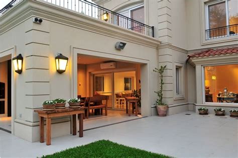 An Outdoor Patio With Potted Plants And Lights On The Side Of It