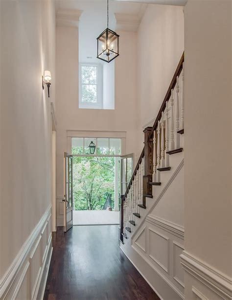 A Hallway Lined With White Wainscoting Leads To An Elegant Two Story