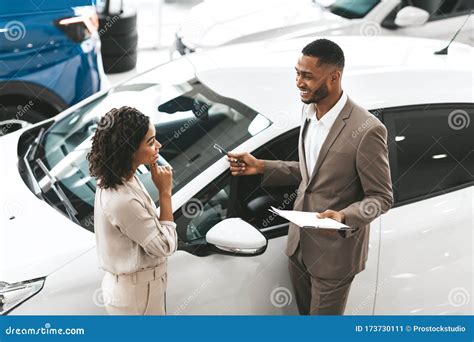 Auto Verkaufsleiter Showing Auto To Dame Standing In Dealership