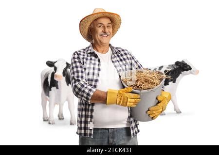 Mature Farmer With Cows Holding A Bucket Full Of Hay And Gesturing