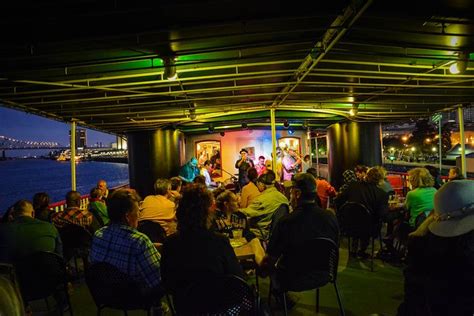 a group of people sitting at tables under an awning with the ocean in ...