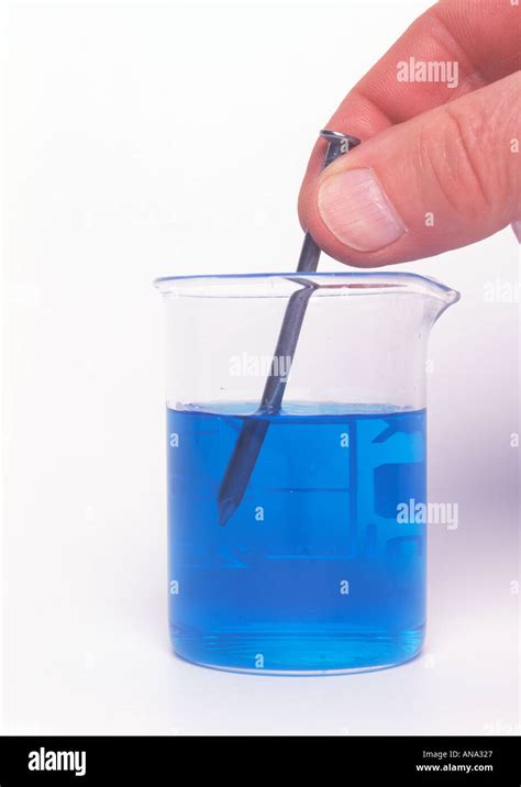 An Iron Nail Being Put Into A Beaker Of Copper Sulphate Solution In Order To Copper Plate It