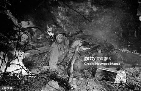 A Soldier Crawls Out From Beside A Dead Companion In A Foxhole He Is