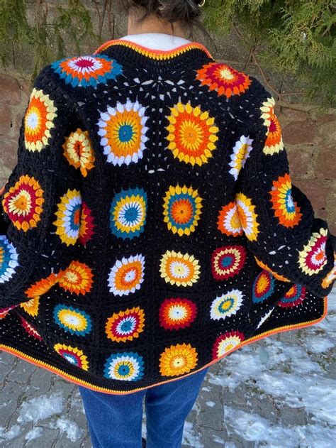 A Woman Wearing A Black Crocheted Blanket With Multicolored Circles On It