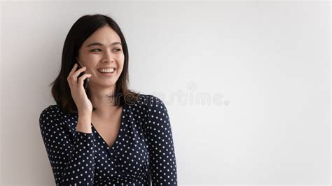 Overjoyed Millennial Asian Female Chatting Holding Mobile Phone To Ear