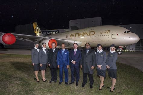 A Group Of Men And Women Standing In Front Of An Airplane On The Tarmac