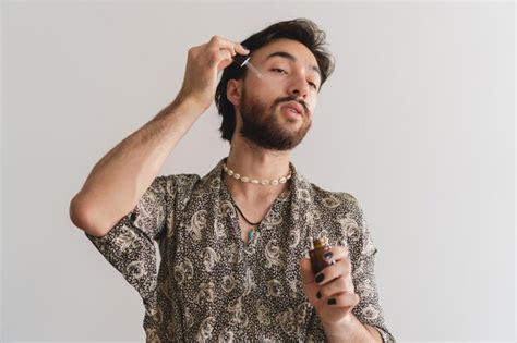 Joven Latino Queer Gay Aplicando Aceites En La Cara Con Un Cuentagotas Sobre Un Fondo Blanco