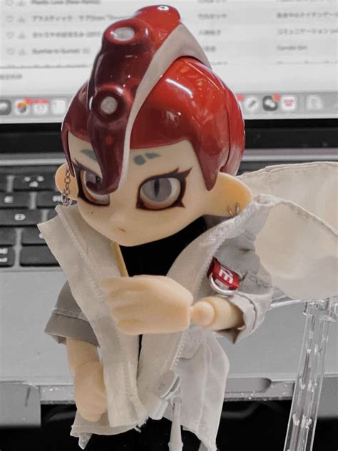 A Toy Figurine Holding A Piece Of Paper In Front Of A Laptop