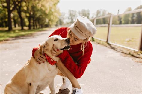 Belle blonde embrassant tendrement son chien sur le chemin du parc en automne Fille élégante se