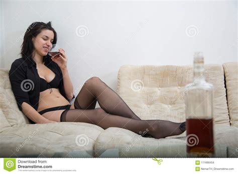 Girl In Black Provocative Lingerie Sitting On Sofa In Apart Stock Photo
