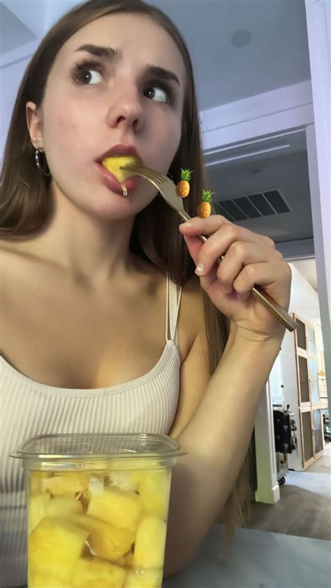 A Woman Holding A Spoon With Some Fruit In It