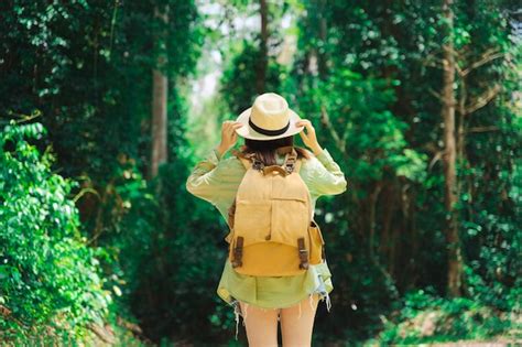 Mujer viajera con mochila sosteniendo sombrero y mirando increíbles