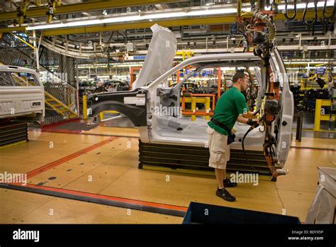 A Factory Worker Installs Door Hardware On An F 150 Pickup Truck At The