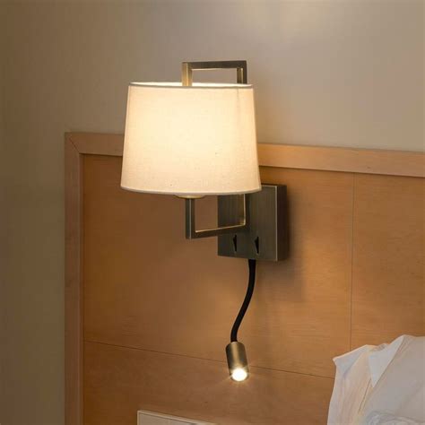 A Lamp That Is On The Side Of A Wall Next To A Bed And Pillows