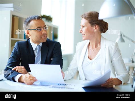 Two Mature Business Partners Discussing Document In Office Stock Photo