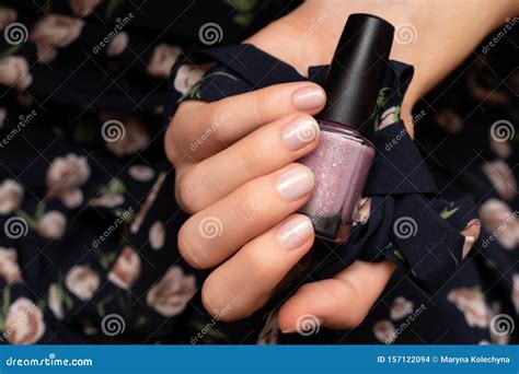 Female Hand With Glitter Nail Design Holding Nail Polish Bottle Stock