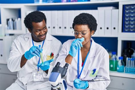 African American Man And Woman Scientists Writing On Document Holding