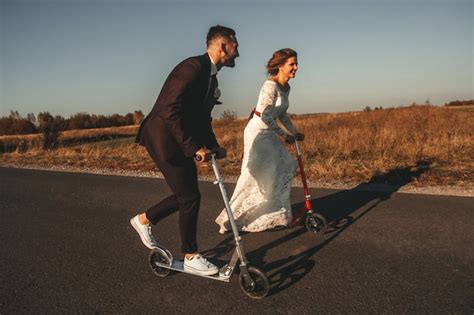 Pareja De Novios Sonriente Montando En Scooters A Lo Largo De La