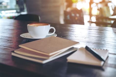 Premium Photo Notebooks Pen And Coffee Cup On Wooden Table In Cafe