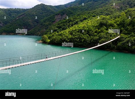 Boy Walking On Hanging Or Suspension Bridge Over Beautiful Emerald