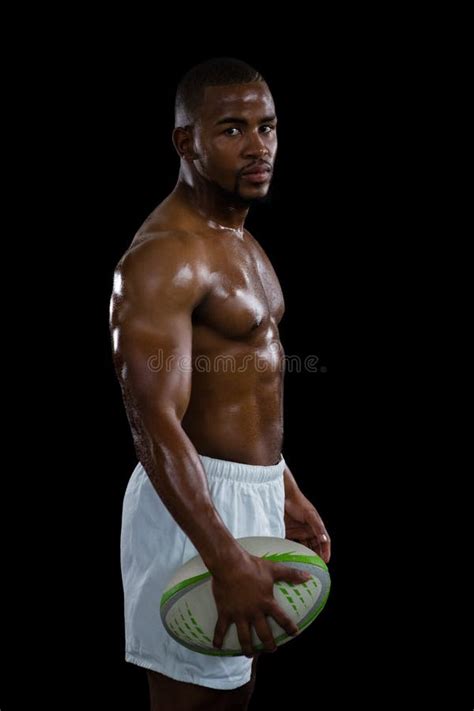 Portrait Of Shirtless Male Athlete Holding Rugby Ball Stock Photo