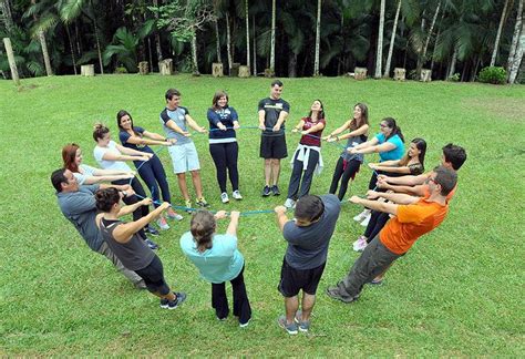 A Group Of People Standing In A Circle On Top Of A Lush Green Field