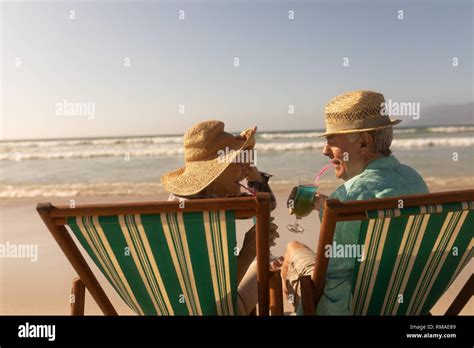 Senior Couple Having Cocktail Drink While Relaxing On Sun Lounger At