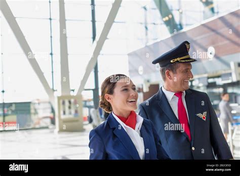 Portrait Of Mature Pilot And Attractive Flight Attendant Walking While