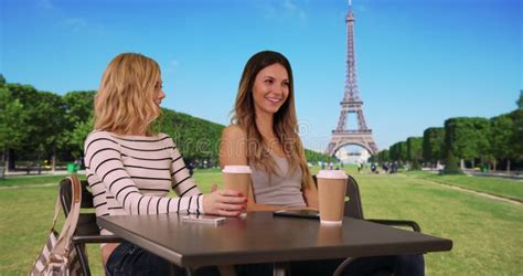 Lovely Brunette Woman And Blonde Friend Socializing Near Eiffel Tower