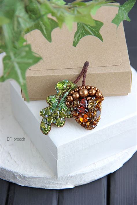 Two Beaded Brooches Sitting On Top Of A White Box Next To A Plant