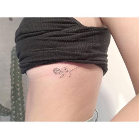 Fine Line Rose Tattoo Located On The Rib