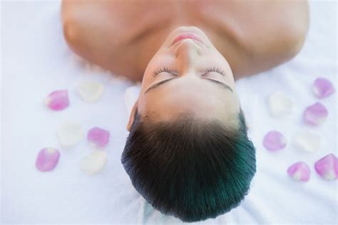 Premium Photo Calm Brunette Lying On Towel With Rose Petals