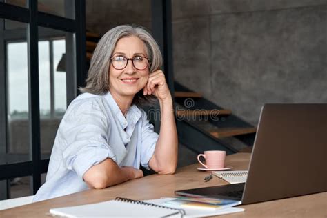 Smiling Mature Middle Aged Woman Sitting At Workplace With Laptop