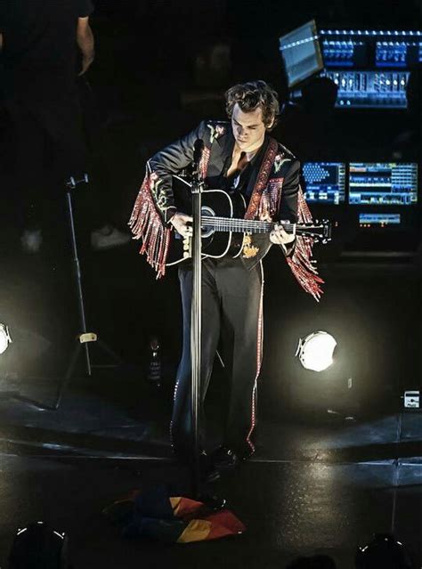 A Man Standing On Top Of A Stage Holding A Guitar