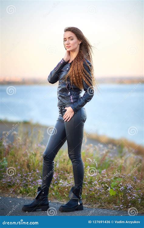 La Belle Fille Sexy Avec De Longs Cheveux Dans Une Veste En Cuir Et Un Cuir Halète La Position