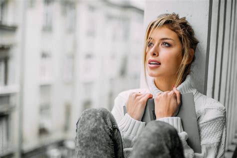 Beautiful Blonde Woman Reading A Book At Her Home Balcony By Stocksy