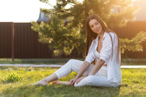 Premium Photo Portrait Of Smiling Woman Sitting On Grass Against Plants