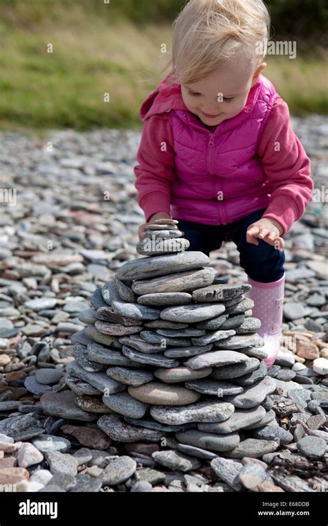 Young Child Stacking Rocks On A Pebble Beach Stock Photo Alamy