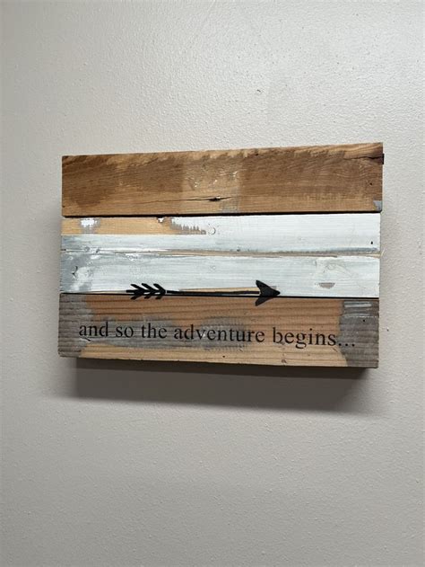 A Wooden Sign That Says And So The Adventure Begins With An Arrow