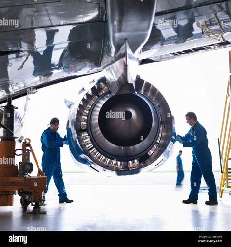 Engineers Working On Aircraft Engine In Aircraft Maintenance Factory