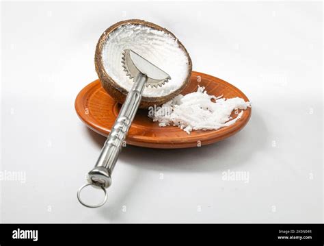 Grated Coconut In A Mud Plate With A Coconut Hand Grater On White