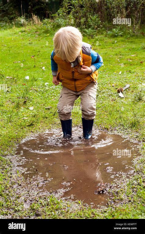 Boy having fun splashing in muddy puddles Stock Photo - Alamy