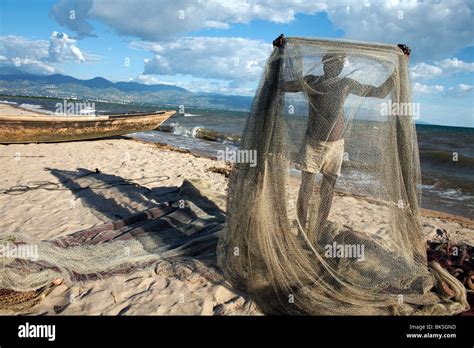 A Fisherman Tends His Nets On Plage Des Cocotiers Also Known As Saga