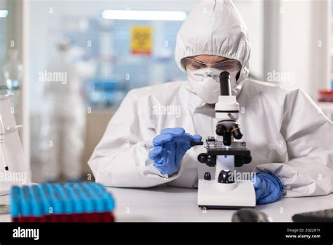 Healthcare Scientist Dressed In Ppe Suit Working Using Microscope In