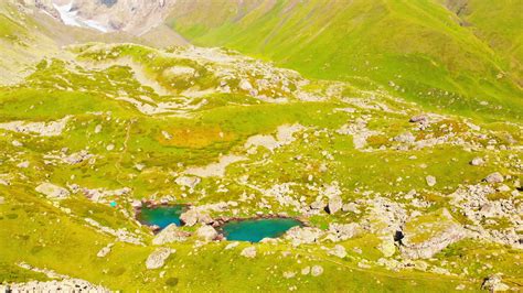 Aerial views scenic green glacier lake with tent standing in Kazbegi national park. Camping and ...