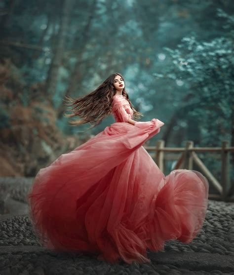 A Woman In A Long Red Dress Is Standing On The Ground With Her Hair